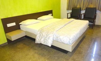a bed with white sheets and pillows is in a room with a green wall at Hotel Greenpark