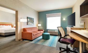 a small hotel room with a couch , a television , a desk , and a dining table at Home2 Suites by Hilton Ogden