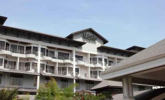 a large hotel building surrounded by grass and trees , with a car parked in front of it at Thistle Port Dickson Resort