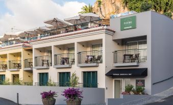 a building with multiple balconies and outdoor seating areas , surrounded by lush greenery and mountains at Pestana Churchill Bay