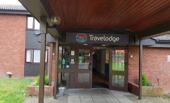 the entrance to a travelodge hotel with a wooden roof and sign above the door at Travelodge Oswestry