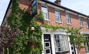 a brick building with a green ivy covered roof , possibly a pub or restaurant , located in a small town at Crofts Hotel