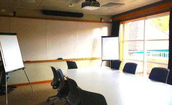 a large conference room with multiple chairs arranged in rows and a projector mounted on the wall at Glenferrie Lodge