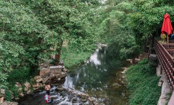 a person is standing in a stream surrounded by lush greenery and trees , with water flowing into the left bank at Zantiis Ndol Villas