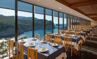 a dining room with tables and chairs set up for a formal meal , overlooking a body of water at Hotel Galeón