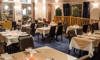 a well - decorated restaurant with tables set for dining , including wine glasses and silverware , as well as candles at The Kings Head Hotel