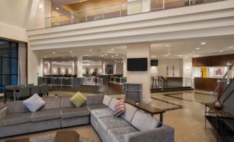 a spacious living room with a large flat - screen tv mounted on the wall , surrounded by couches and chairs at Crowne Plaza Englewood, an IHG Hotel