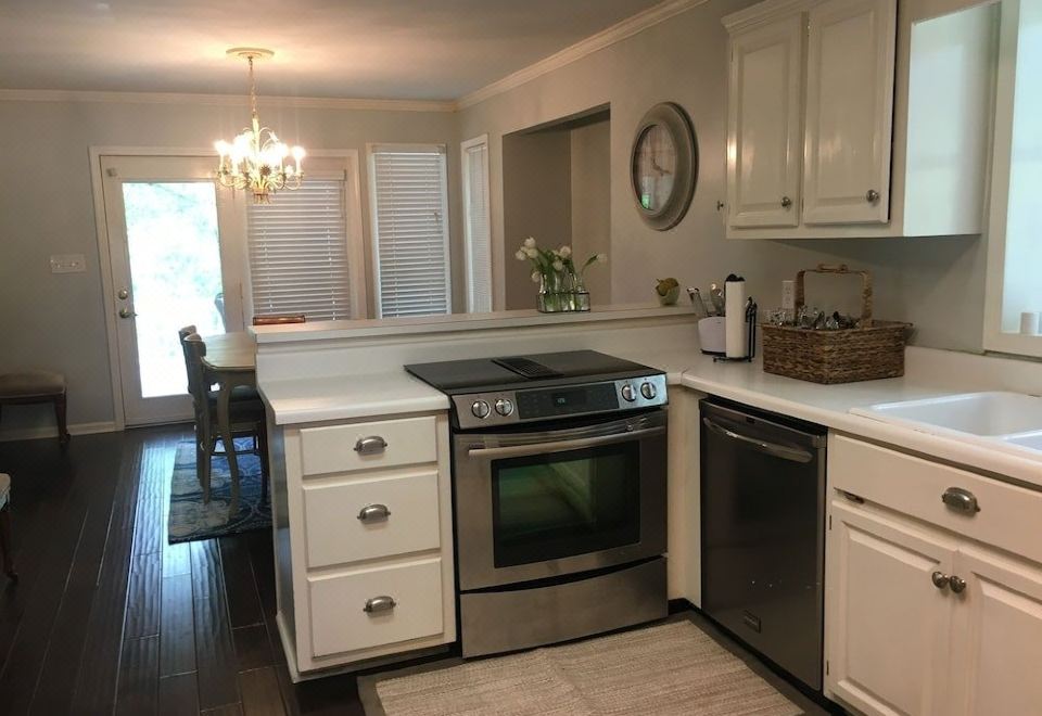 a modern kitchen with white cabinets , black stove , and stainless steel appliances , including a refrigerator , oven , and sink at The Waterford