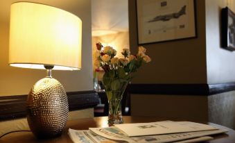 a vase of flowers sits on a table next to a lamp and a newspaper at Recruiting Sergeant