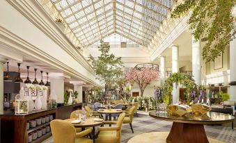 a luxurious hotel lobby with high ceilings , large windows , and multiple dining tables set for guests at Hyatt Regency Birmingham