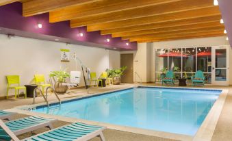 a large swimming pool with a wooden ceiling and colorful lounge chairs surrounding it , creating a relaxing atmosphere at Home2 Suites by Hilton Youngstown West/Austintown