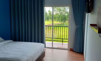 a bedroom with a large window and sliding glass door , overlooking a grassy area outside at JC Resort