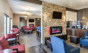 a modern hotel lobby with a large stone fireplace , multiple dining tables , and comfortable seating at Comfort Inn & Suites North Aurora - Naperville