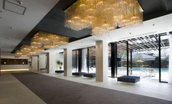 a modern hotel lobby with a long hallway , multiple couches , and a large chandelier hanging from the ceiling at Hotel Fuji