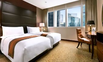 a hotel room with two beds , one on the left and one on the right side of the room at Oakwood Premier Cozmo Jakarta