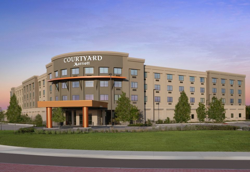 a large hotel with a courtyard by marriott sign on the front , surrounded by grass and trees at Courtyard Austin Pflugerville and Pflugerville Conference Center