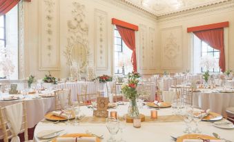 a large , elegant dining room with multiple tables set for a wedding reception , each table covered in white tablecloths and adorned with gold at Lumley Castle Hotel