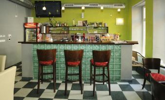 a bar area with green walls , black and white checkered floor , and three wooden bar stools at Hotel City