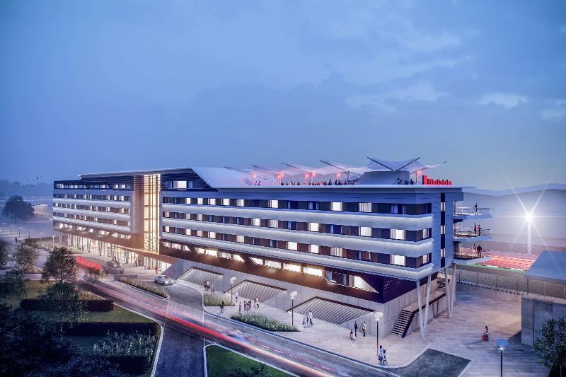 a modern hotel building with multiple floors , surrounded by trees and other buildings in the background at Hilton Garden Inn Silverstone