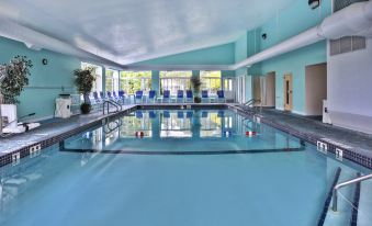a large indoor swimming pool with a white tiled floor and blue walls , surrounded by lounge chairs at Holiday Inn Express Mackinaw City