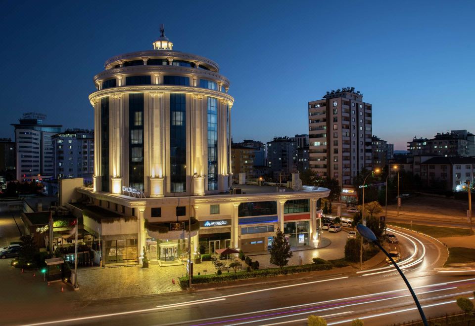 a city street at night with a tall building in the background , illuminated by street lights at DoubleTree by Hilton Gaziantep