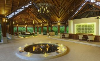 a large room with a circular fountain in the center and candles on the sides at Dusit Thani Maldives