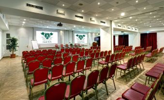 a large conference room filled with rows of red chairs arranged in front of a projector screen , ready for a meeting or presentation at Grand Hotel Arenzano