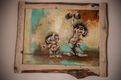 two small children , one holding a hammer and the other lifting a kettlebell , are depicted in a painting on a wooden frame at Troll