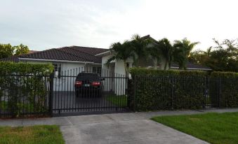 a black car is parked in front of a house with a black fence and palm trees at Modern Cabins
