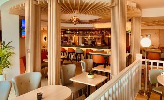 a restaurant with white tables and chairs , a bar , and a staircase leading to an upper level at Bayview Hotel