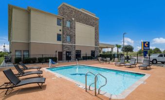 a large swimming pool with a diving board and lounge chairs in front of a hotel at Comfort Inn & Suites Victoria North