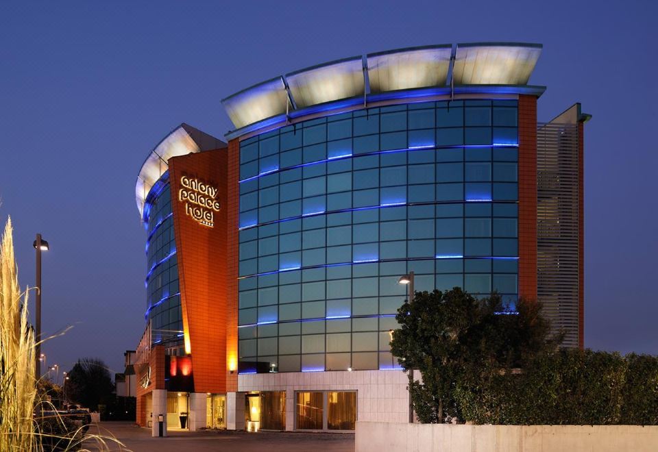 a modern building with a curved facade and large windows , illuminated by blue lights at night at Antony Palace Hotel - Venice Airport