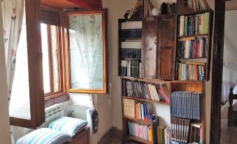 a cozy corner with a window seat , bookshelf filled with books , and a painting on the wall at Casa Rural la Plazuela de Mari