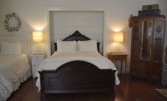 a large bed with a wooden headboard and white linens is in a room with two lamps on either side at Southern Rose Ranch