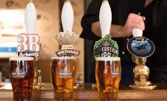 a man standing behind a bar , pouring beer from a tap into a glass at Helen Browning's Royal Oak