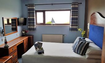 a clean and well - organized bedroom with a large bed , blue walls , and a window overlooking the ocean at Heights Hotel