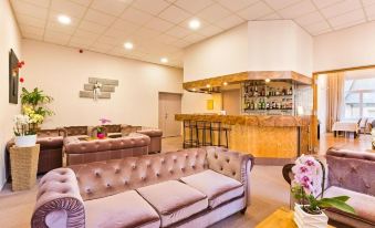 a well - lit lounge area with several couches and chairs , as well as a bar in the background at Hôtel du Parc