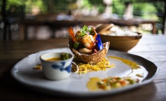 a plate of food on a dining table , including a basket of shrimp and other items at Tam Coc Garden Resort