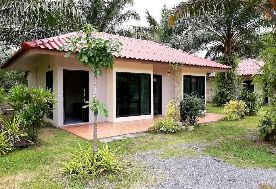 a small house surrounded by green grass and palm trees , located in a tropical setting at Payabangsa Resort