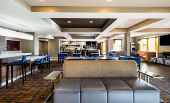 a large , modern hotel lobby with a bar and seating area , complete with couches , chairs , and tables at Sonesta Select Detroit Novi