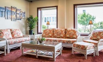 a cozy living room with a white couch , two chairs , a coffee table , and a television at Island Inn & Suites, Ascend Hotel Collection