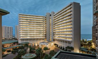 a large hotel building with multiple floors and balconies , situated next to a body of water at Hilton Myrtle Beach Resort