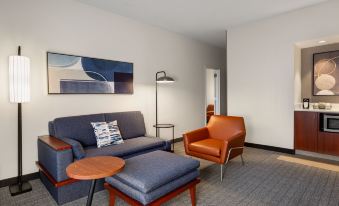 a modern living room with a blue couch , a brown chair , and a wooden coffee table at Courtyard Minneapolis-St. Paul Airport