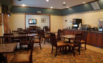 a large dining room with wooden chairs and tables , a television on the wall , and an art installation at Country Inn & Suites by Radisson, Salisbury, MD
