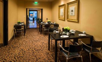 a dining area with tables and chairs , a green exit sign , and framed pictures on the wall at Hotel Concorde