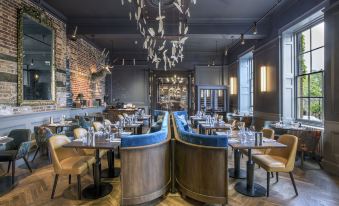 a modern , stylish restaurant with wooden tables and blue booths , black ceiling beams , and large windows at Angel Hotel