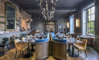 a modern restaurant interior with wooden floors , gray walls , and blue booths , decorated with fish decorations on the ceiling at Angel Hotel