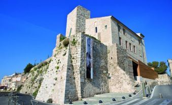 a large stone building with a tall tower and a sign in front of it at Hôtel Restaurant de la Mer