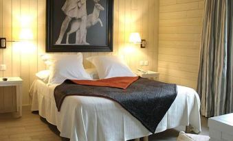 a large bed with white sheets and a black blanket is in a room with wooden walls at La Maison Navarre