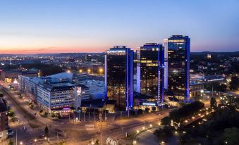 an aerial view of a city at night , with tall buildings illuminated and cars driving on the road at Gothia Towers & Upper House